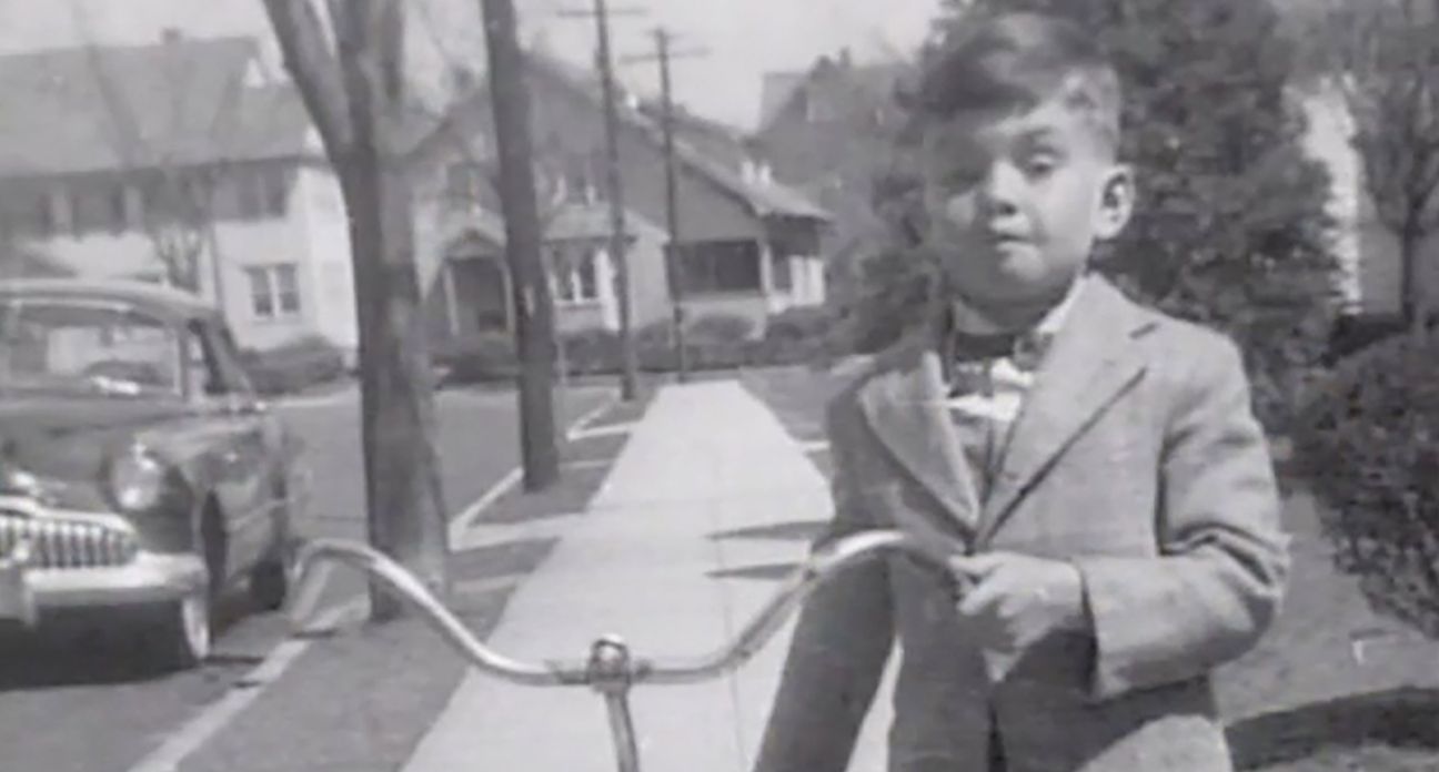 A childhood photo of Brian Kennedy next to a bicycle.