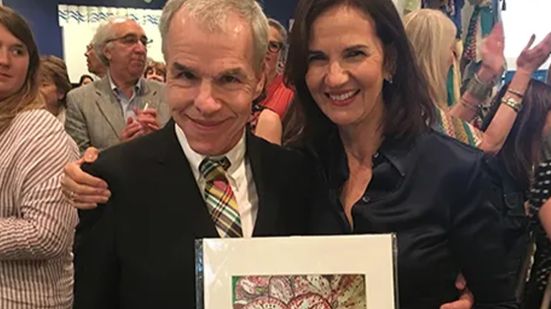 A man and a woman holding a piece of artwork at MDAC's Enchanted Festival of Trees event.